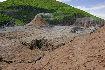 Die aus älterem Gestein bestehende Kraterwand des grünen Rückens zwischen Nord- und Südkrater im Hintergrund. Eine Person als Maßstab. (Photo: Tom Pfeiffer)