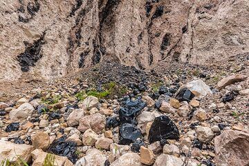 Obsidian veins in the lava flow breccia and pieces on the ground. (Photo: Tom Pfeiffer)