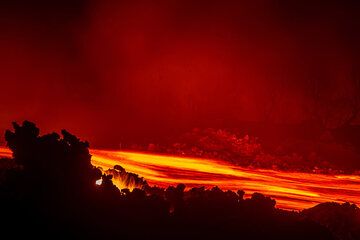 Fließende Lava in der Nacht; Helle Flammen von noch brennendem Holz, das unter der Strömung vergraben ist, entweichen durch Lücken zwischen den Lavablöcken an den erkalteten Rändern der Strömung. (Photo: Tom Pfeiffer)