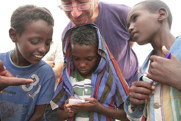 Marco and 3 young boys writing their names. (Photo: Tom Pfeiffer)