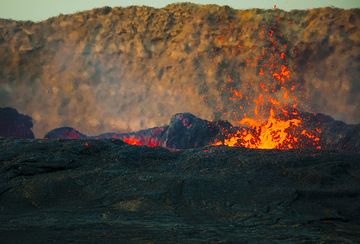 Lava fountains on the perched lake of Erta Ale in the morning. The caldera wall in the background. (Photo: Tom Pfeiffer)