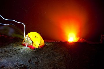 Michael's tent perched on the crater of active Erta Ale volcano with its erupting lava lake in the center of the crater. The light of a person with a flashlight walking into the tent leaves a trace on the film. (Photo: Tom Pfeiffer)