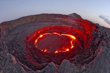 Le volcan dans la soirée du 28 novembre 2009. Le lac de lave est dans une phase de renversement de la croûte et la lave rougeoyante illumine les parois circulaires du cratère. (Photo: Tom Pfeiffer)