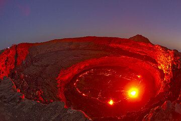 Der rote Schein der Lava beleuchtet die runden Kraterwände im abendlichen blauen Zwilicht. Beobachter am linken Kraterrand. (Photo: Tom Pfeiffer)