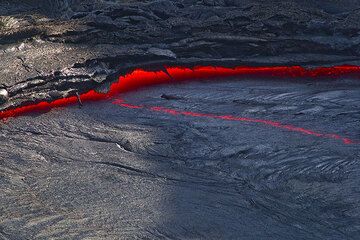 After each fountaining episode, degassing the lake, the volume shriks and the lake drops by about a meter, leaving dangling lava stalactites on the levees along the margins. (Photo: Tom Pfeiffer)