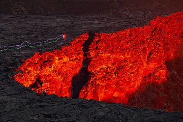 Teile des angestrahlten Kraters bei Nacht. Die Leuchtspuren von Taschenlampen einiger Beobachter, die den Rand verlassen, sind sichtbar.  (Photo: Tom Pfeiffer)