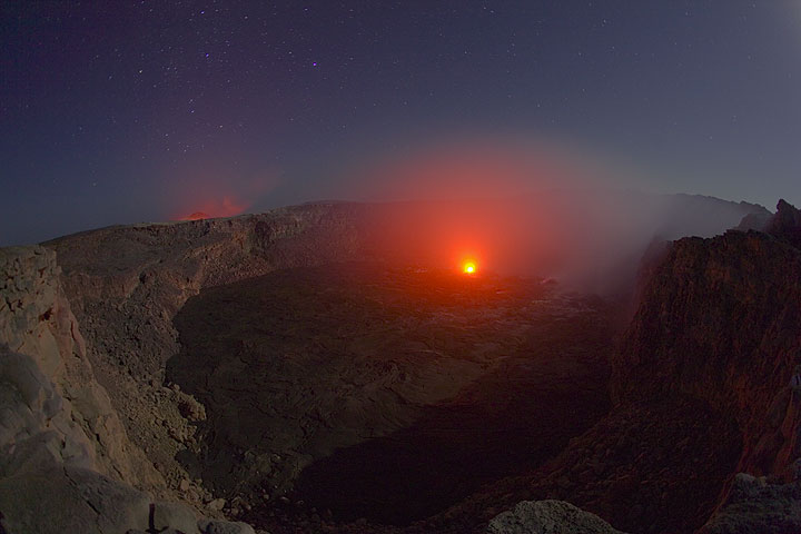 Glow from an active hornito in the south crater and the lava lake in the background at full moon
