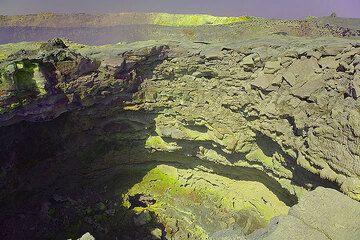 Feiner Schwefel überzieht Bereiche des inneren Kraterrands eines Pitkraters in der Nähe des Nordkraters (im Hintergrund). Auch die Kalderawand im Hintergrund ist von gelbem Schwefel überzogen. (Photo: Tom Pfeiffer)