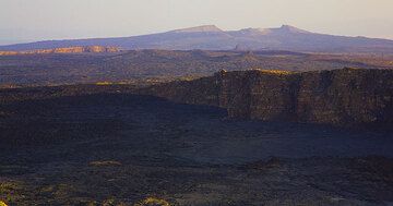 Le coucher du soleil touche les bords supérieurs de la caldeira du volcan Erta Ale. Derrière se trouve une autre caldeira et le volcan bouclier Hayli Gubbi au fond avec sa propre caldeira sommitale. (Photo: Tom Pfeiffer)