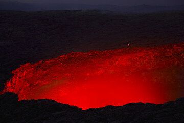 Beobachter auf dem Kraterrand am Abend, der von der Lava des Sees angeleuchtet ist. (Photo: Tom Pfeiffer)