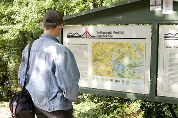Tom Pfeiffer steht vor einer Tafel, die den Vulkanismus der Ost-Eifel erklärt (Photo: Tobias Schorr)