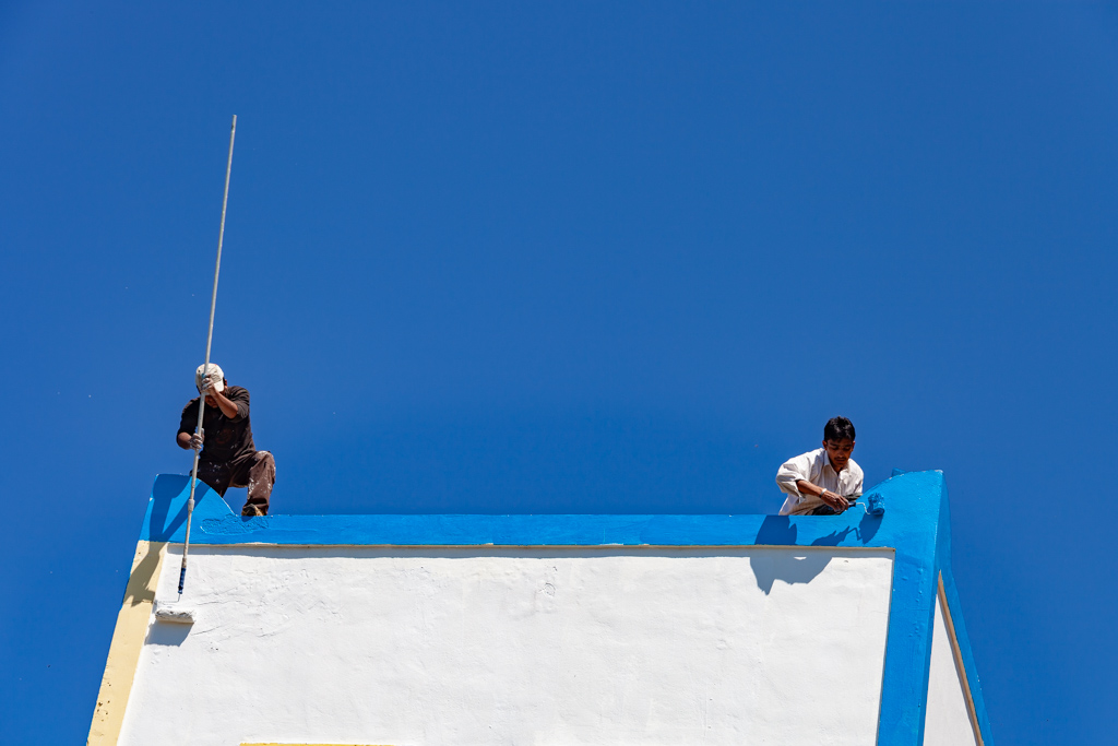 Refugees painting an old house in Zia. (Photo: Tobias Schorr)