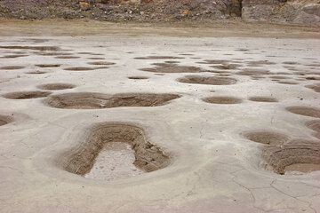 The crater floor is dotted with holes containing boiling mud. (c)