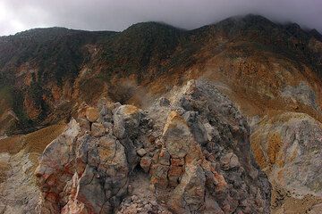 View onto the peak of the lava dome and the peak of the mountain, still shredded in clouds. (c)