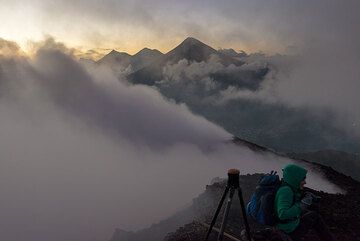 Steam fills the crater of Pacaya (21 Dec 2015) in the evening; in the background, the trio of Fuego, Acatenango and Agua stratovolcanoes peak over the cloud deck. (Photo: Tom Pfeiffer)