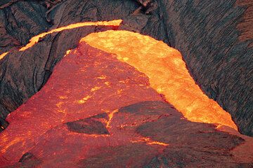 Flüssige Lava ergießt sich über die erstarrte Kruste. Das Gewicht der Lava drückt auf den Rand der Krustenplatten und lässt diese zerbrechen, was eine Kettenreaktion zur Folge hat, bei der nach und nach Segmente von der Krustendecke abbrechen und in das Innere einsinken. (Photo: Tom Pfeiffer)