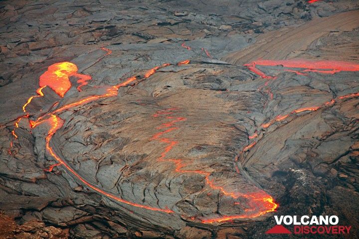 The active lava lake at dusk. The crust is so thin, that the red glow breaks through in many places; at the left side, parts of the crust are being overturned. (Photo: Tom Pfeiffer)