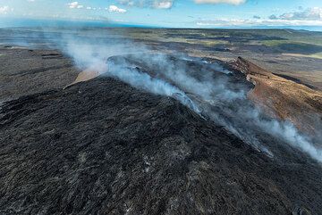 With time, lava has continued to fill the Pu'u 'O'o crater, overspilling large parts of the eastern (foreground) and western (background) rims. Gasses escaping from the vents feeding the active Kahauale'a lava flows to the lower right. (Photo: Tom Pfeiffer)