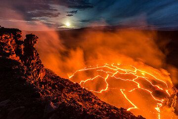 The lava lake and the moon setting above the distant silhouette of Mauna Loa shield volcano. (Photo: Tom Pfeiffer)