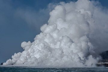An impressive steam plume is rising from Kamokuna sea entry at Kilauea volcano, Hawai'i.
The lava erupts to the surface at the volcano's eastern rift zone at the Pu'u O'o vent and flows for many miles through an underground lava tube until it reaches the coast. 
The lava entry shown here has been going on since July 2016 and has been enlarging the Island of Hawai'i by building a fragile delta of new land. (Photo: Tom Pfeiffer)