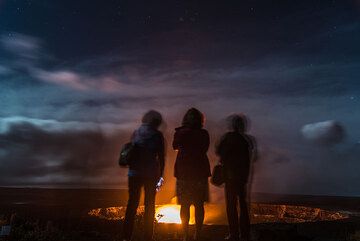 A group of friends stand on the terrace watching the lava lake in front of them. (Photo: Tom Pfeiffer)