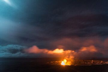 Denser and lower clouds drift over the lava lake and are pained red and yellow. (Photo: Tom Pfeiffer)