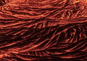 Lava pahoehoe brillante y viscosa del volcán Kilauea (Hawái) por la noche (marzo de 2017).
Este tipo de textura de lava se encuentra comúnmente en los volcanes en escudo hawaianos que producen vastos campos de flujo de lava de lava basáltica relativam (Photo: Tom Pfeiffer)