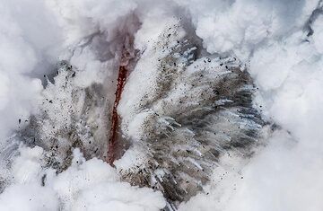 The lava hose exits the exposed lava tube in the upper cliff and then free falls in a steep, curved arch about 15 meters down into the ocean. (Photo: Tom Pfeiffer)