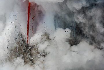 Where the lava hose plunges into the sea, it triggers near-constant (so-called "littoral") explosions, throwing dark masses of still-hot, steaming lava fragments and water into the air. (Photo: Tom Pfeiffer)