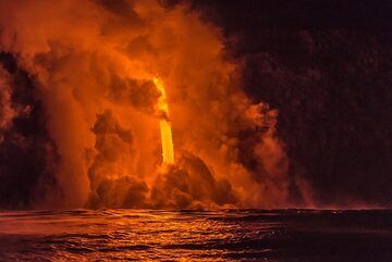 The fire hose is going strong, forming an arched jet of molten gold pouring into the sea. The water is red with reflection. (Photo: Tom Pfeiffer)