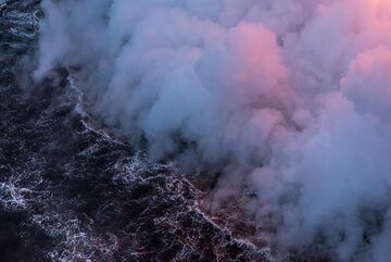Bluish and pink steam from the lava entry hovering above the ocean surface. (Photo: Tom Pfeiffer)