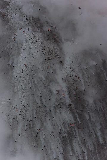 Dense steam and a myriad of black rocks falling from it. (Photo: Tom Pfeiffer)
