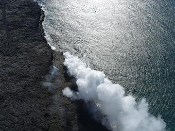 Extension day 3: The Kamukona lava ocean entry from the air. with a large steam plume generated where different streams of lava pour into the ocean and smaller fumarolic activity at the top of the new platform where the main lava feeder tune arrives (Photo: Ingrid Smet)