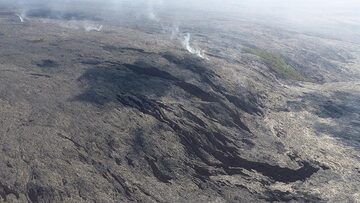 Jour d'extension 3 : Les coulées de lave plus anciennes qui descendaient du pali ont laissé derrière elles une kipuka (île de végétation). Les éruptions de lave de surface plus récentes sont reconnaissables à leur couleur brun foncé à noire, la traînée de vapeur indique où la lave s'écoule sous terre dans des tubes de lave jusqu'à l'entrée de l'océan à Kamukona. (Photo: Steven Van den Berge / Lana Van Heghe)