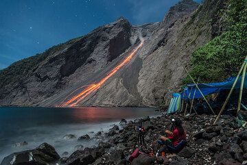 Desprendimientos de rocas resplandecientes después de una agradable erupción nocturna; nuestro campamento a la derecha. (Photo: Tom Pfeiffer)