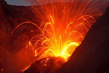 Another strong eruption at night, throwing out a meter-sized bomb (thick trail leaving the vent to the right side). (Photo: Tom Pfeiffer)