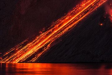 Glowing lava avalanches and reflection on the sea, Batu Tara volcano Nov 2014 (Flores Sea, Indonesia) (Photo: Tom Pfeiffer)