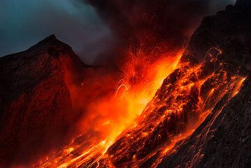 Des bombes lumineuses atterrissent sur la paroi extérieure du cratère et glissent le long de la sciara après une forte explosion à Batu Tara (novembre 2015) (Photo: Tom Pfeiffer)