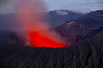 Los respiraderos brillantes iluminan de color rojo brillante el vapor difuso y la columna de cenizas sobre el cráter de Bromo durante la noche. (Photo: Tom Pfeiffer)
