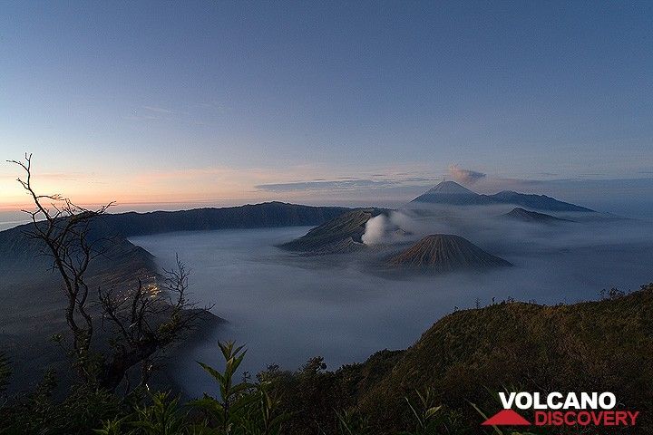 The fog-filled Tengger caldera just before sunrise. To the left, lights of the village Cemoro Lawang on the caldera rim. (c)