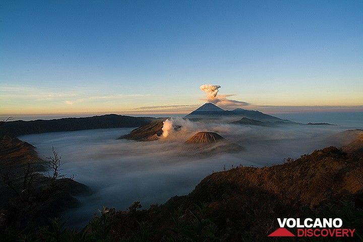 Sonnenlicht erreicht die Spitzen über der nebelgefüllten Kaldera (c)