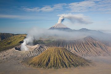 Ein Ausbruch des Semeru mit dem rauchenden Bromo und den zerfurchten Kegel des Batok im Vordergrund. (Photo: Tom Pfeiffer)