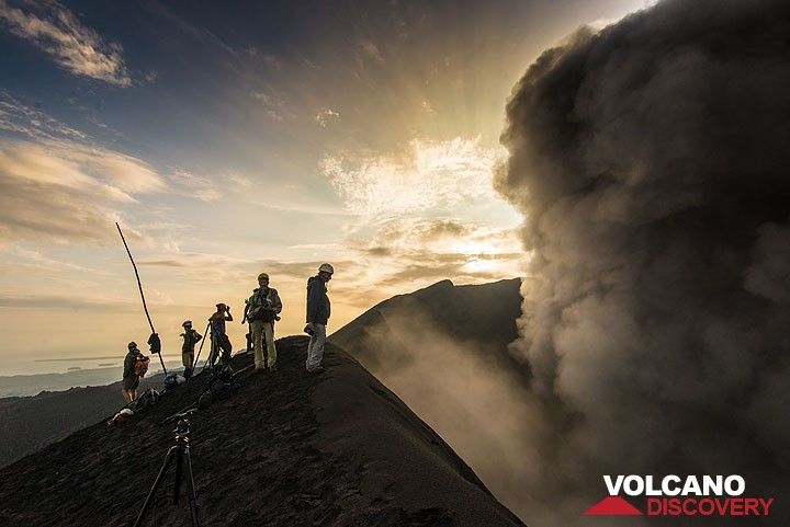 Group at the crater rim at sunrise with an eruption plume rising from the crater. (Photo: Tom Pfeiffer)