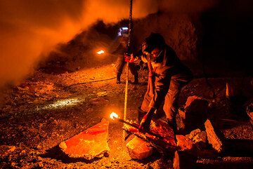 A metal bar is used to break larger pieces of sulfur crust. (Photo: Tom Pfeiffer)