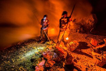 Der Vulkan Ijen in Ost-Java ist berühmt für seinen sauren Kratersee und die großen Schwefelablagerungen, die sich um sehr aktive Fumarolen in der Nähe des Seeufers bilden.
Der Schwefel im Krater wird abgebaut. Nachts brennen einige der Fumarolen mit intensiv bläulichen Flammen durch brennenden Schwefel. Dies ist teilweise auf Selbstentzündung aufgrund der sehr hohen Temperaturen an den Fumarolenöffnungen zurückzuführen, vor allem aber darauf, dass die Arbeiter den Schwefel anzünden, um ihn zu schmelzen und aus den gefrorenen Pfützen zu sammeln, die sich dann auf dem Boden darunter bilden. (Photo: Tom Pfeiffer)