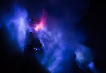 Occasionally, red sparks from liquid, burning drops of sulfur mix into the blue flames. (Photo: Tom Pfeiffer)