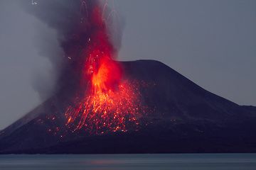An eruption showers the s flank of the summit cone with incandescent cinders. Small lightning discharges in the eruption plume. (Photo: Tom Pfeiffer)