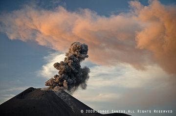 The ash cloud from the previous eruption is illuminated by the setting sun while the crater erupts a weak plume of ash. (Photo: Jorge Santos)