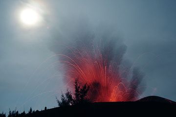 Éruption de l'ANAK Krakatau avec le clair de lune dans le ciel. Les arbres sur la pente externe de l'ancien cratère de ANAK Krakatoa forment une silhouette contre l'éruption.
 (Photo: Tom Pfeiffer)