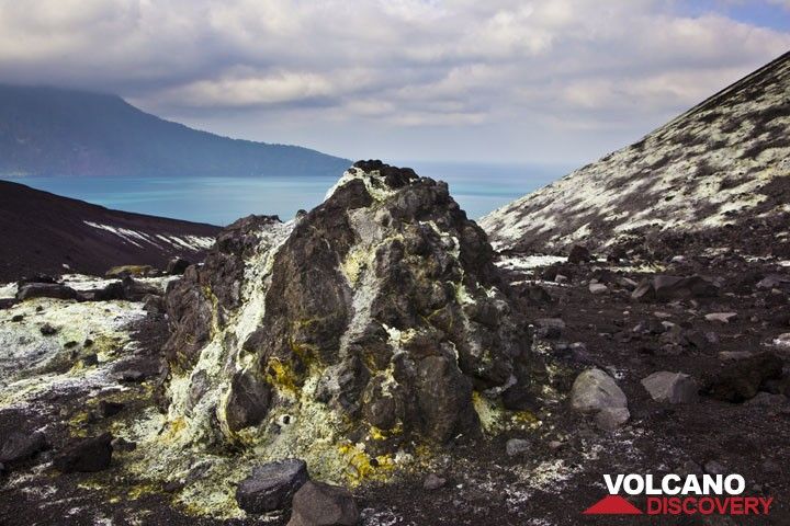 A large bomb in the saddle between the old crater rim and the main cone of Anak has been covered by white and yellow sulfate deposits. (Photo: Tom Pfeiffer)
